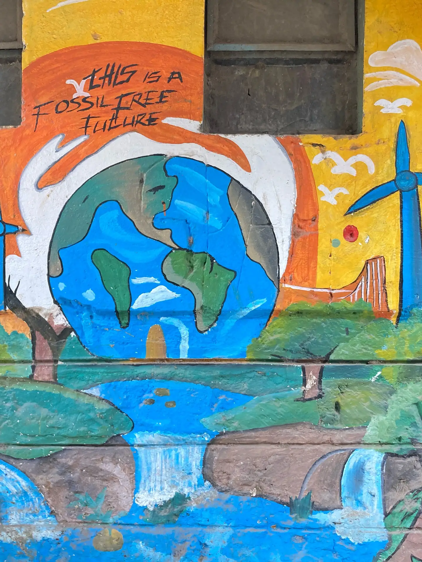 A vivid neighbourhood mural imagines a fossil-free future around a globe and flowing water.