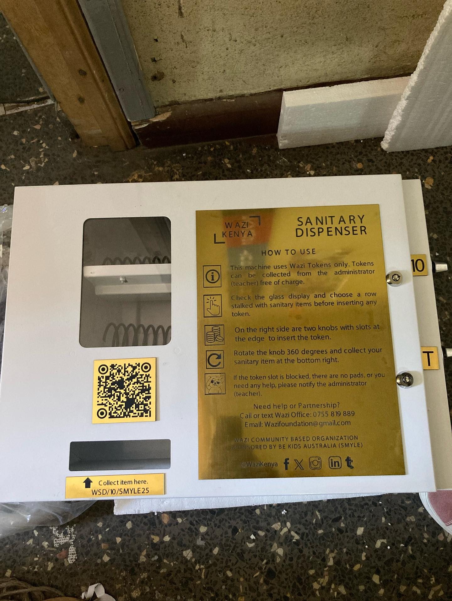 A Wazi sanitary dispenser being installed on a school wall.