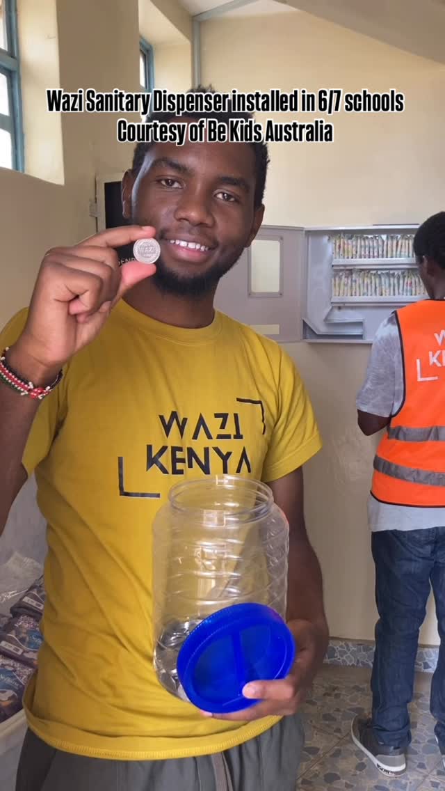 A Wazi sanitary dispenser installed on a school wall in Ruaraka, with the orange Wazi branding and instruction label.