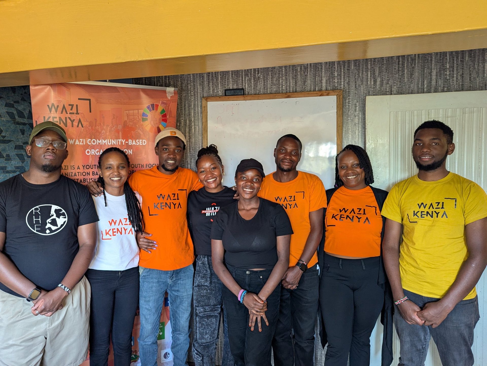 A Wazi management team portrait in branded tees with the org banner behind them.